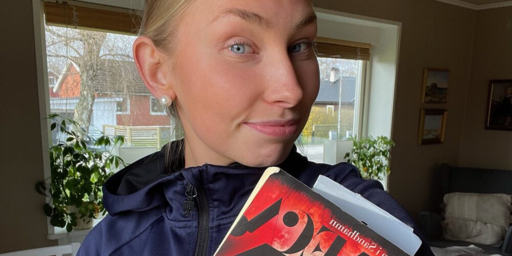 Amanda håller en bok i handen, iklädd FBC tröja.