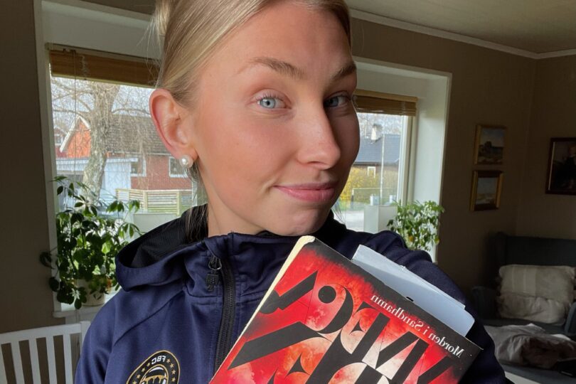 Amanda håller en bok i handen, iklädd FBC tröja.