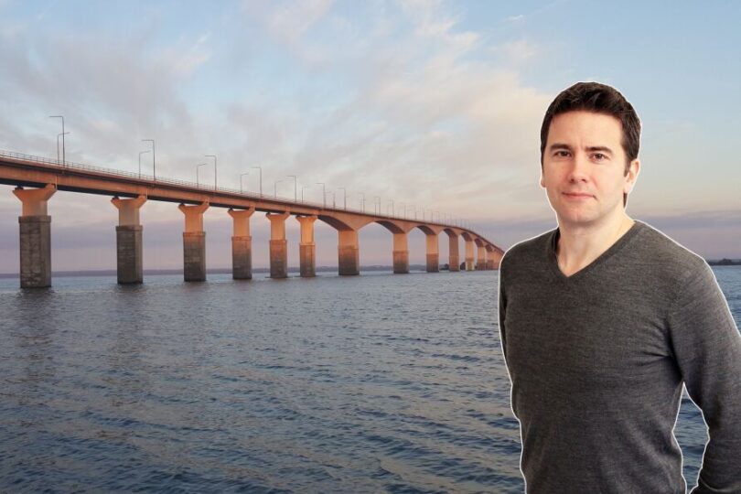 #syntolkning Peter har brunt kort hår och bär en grå tröja. Bakom Peter skymtar Ölandsbron och Kalmarsund.