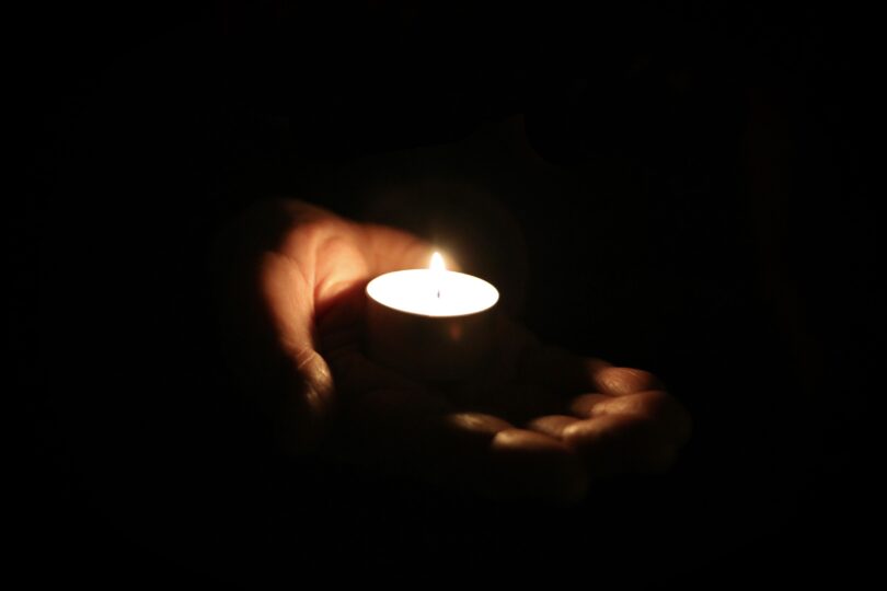 En hand från en person som hålleri ett tänt värmeljus.