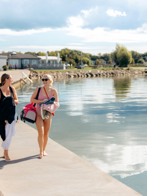 Två kvinnor i badkläder går längs piren i Färjestadens hamn Foto: Alexander Hall