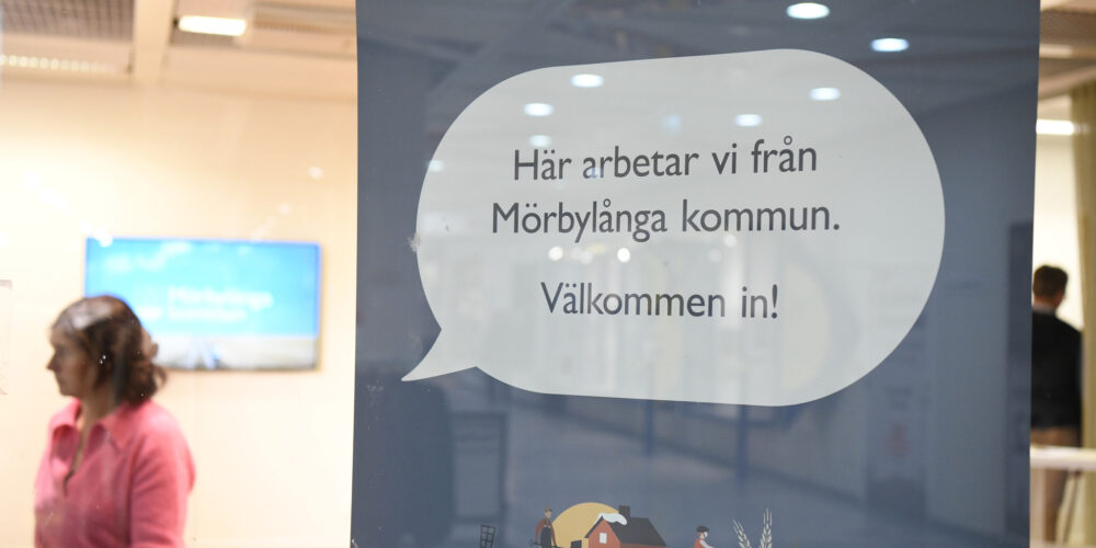 En pratbubbla i ett skyltfönster med text som säger: Här jobbar vi från Mörbylånga kommun, välkommen in!