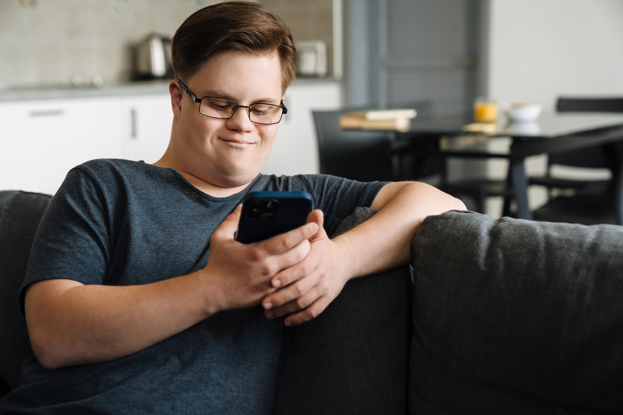 Ung kille som sitter med telefon i soffan