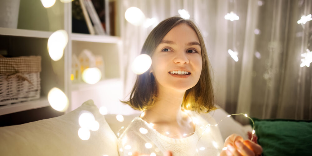 En tonårstjej grejar med juldekorationer i en mysig hemmamiljö.