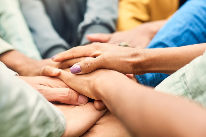 Flera personer står i ring och håller varandras händer.