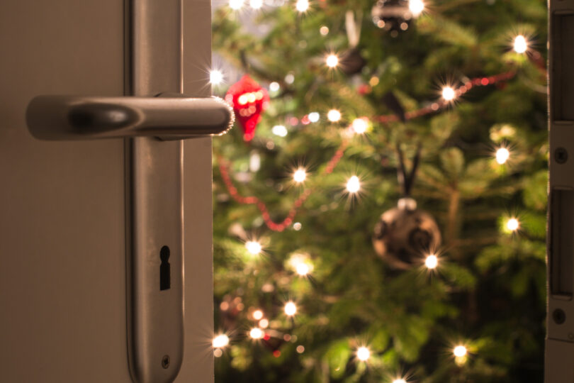 En öppnad dörr där du ser en klädd julgran.