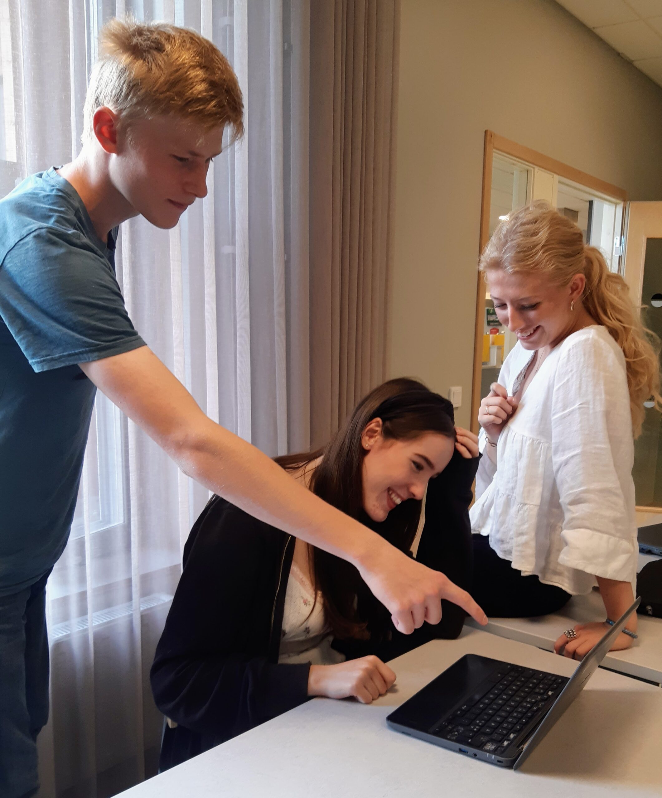 tre elever tittar på en dator.