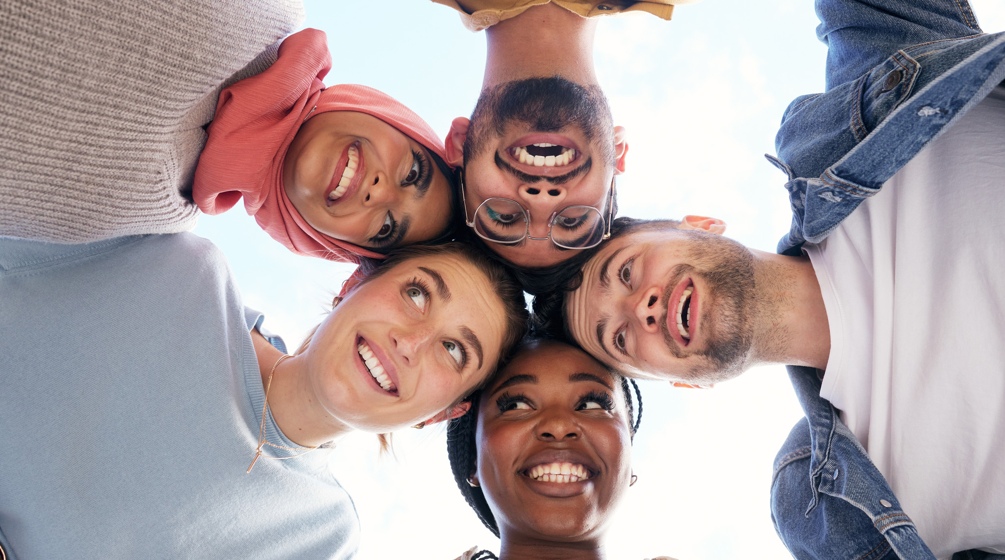 Fem personer står i en cirkel med sina huvuden mot varandra.