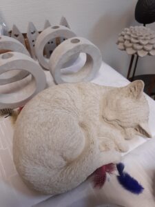 Betongkatt i framkant, bakom ljusstakar i betong.