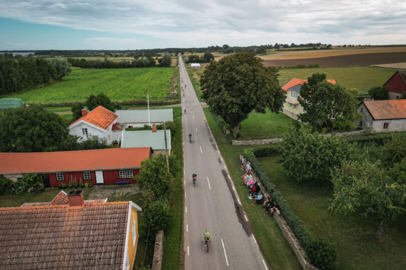 Ironmancyklister fotade uppifrån i Öländsk by med publik vid sidan av vägen.