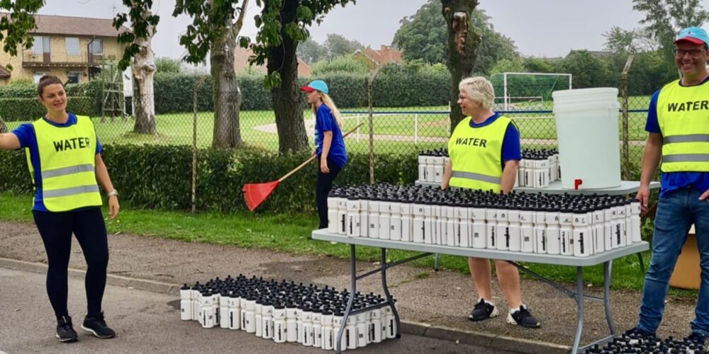 Funktionärer delar ut vattenflaskor vid depån. Foto: Lena