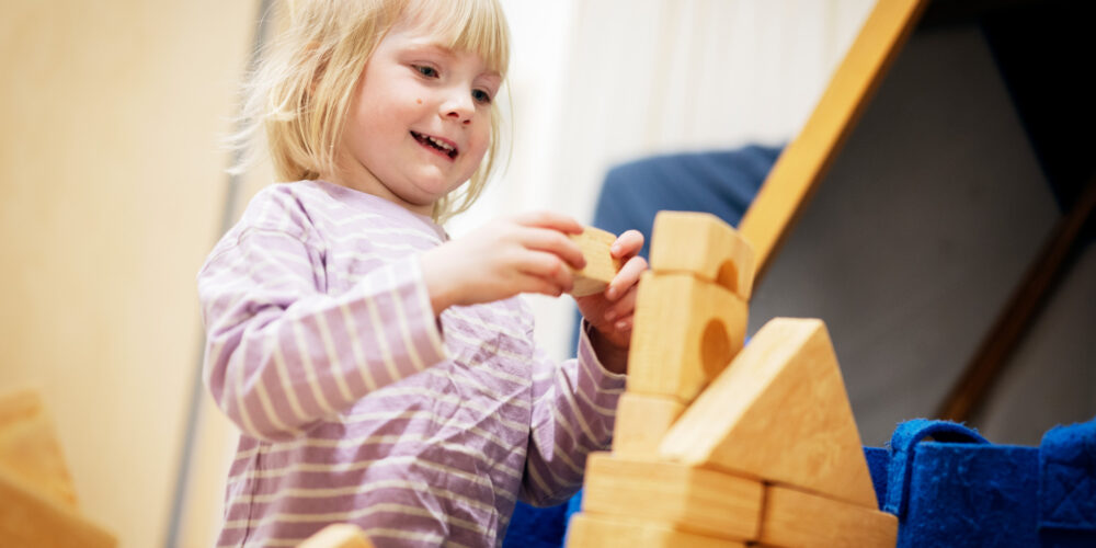 En barn i förskolan bygger med klossar.