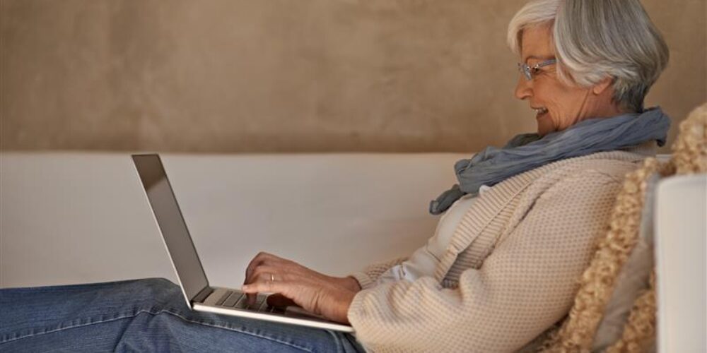 Kvinna i soffa med laptop i knät