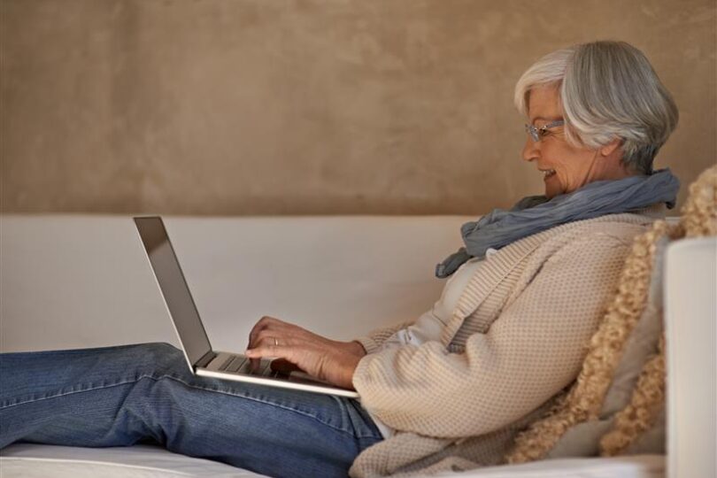 Kvinna i soffa med laptop i knät