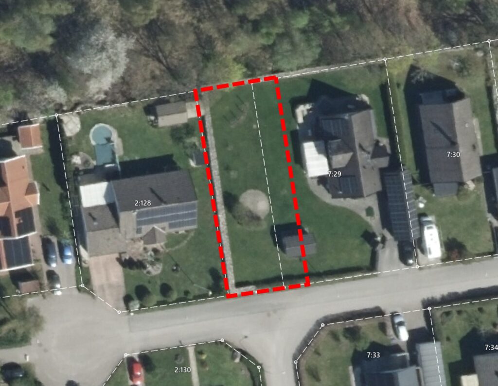 Satellitvy över villakvarter där en tomt markeras med rödstreckad rektangel och vit streckad mittlinje. Fastighetsgränser syns med etiketter “2:128”, “7:29” och “7:30”, intill hus, gräsmattor och väg.
