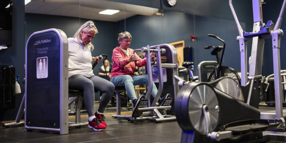 Två seniora kvinnor tränar i ett gym.