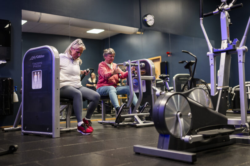 Två seniora kvinnor tränar i ett gym.