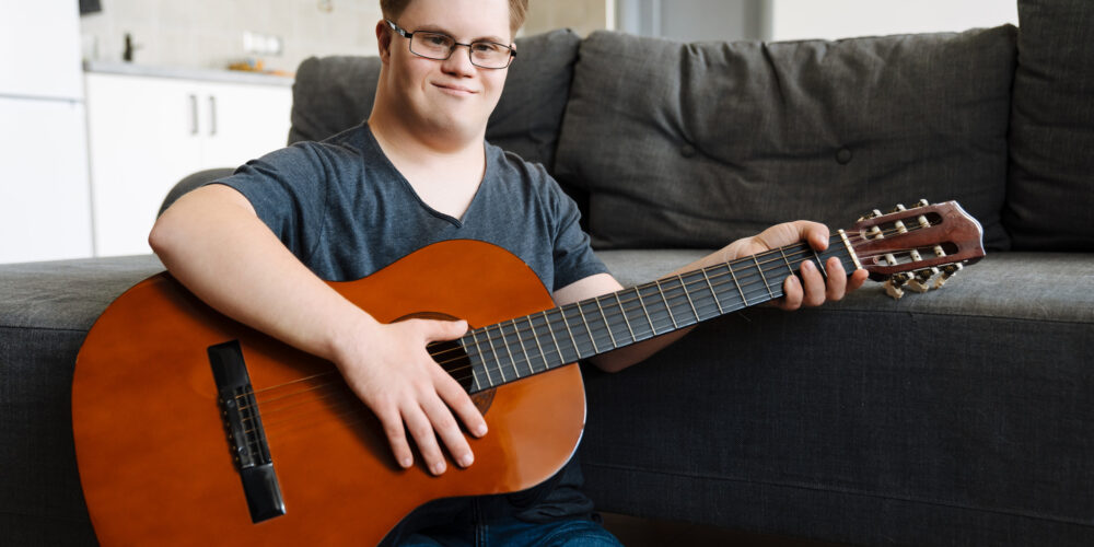 Ung man med Downs syndrom spelar gitarr.