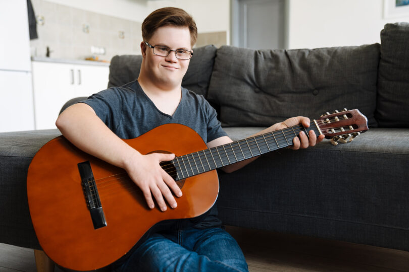 Ung man med Downs syndrom spelar gitarr.