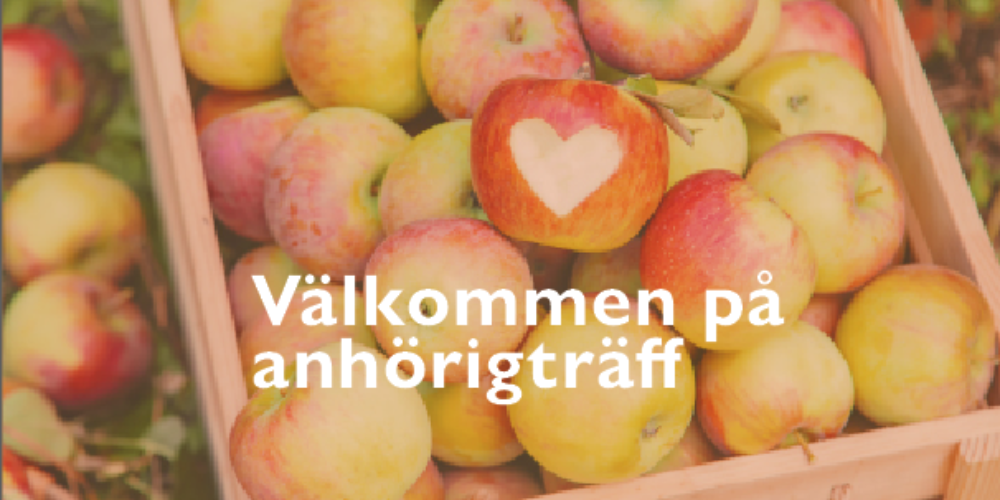 Låda med röda och gröna äpplen ligger tätt packade, med ett äpple i mitten som har ett vitt hjärta. Över bilden står texten: “Välkommen på anhörigträff”.