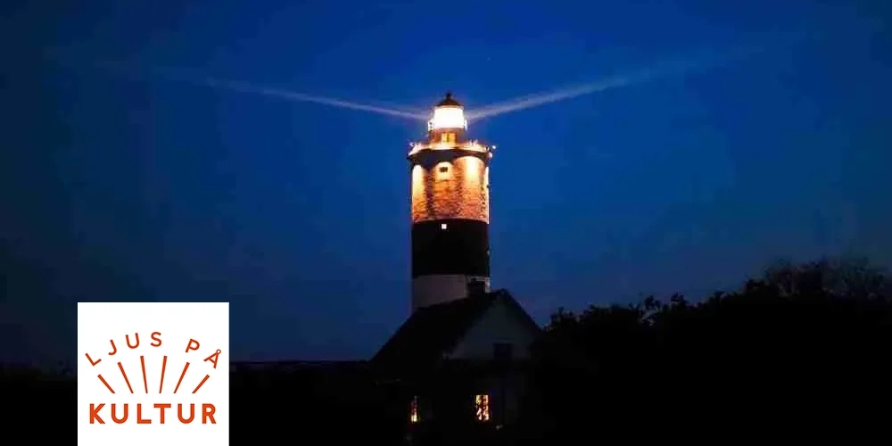 Upplyst fyrtorn lyser ut sina strålar i natthimlen ovanför ett mörkt kustlandskap, med ett hus i siluett nedanför och två upplysta fönster. Logotyp i hörnet med texten: “LJUS PÅ KULTUR”.